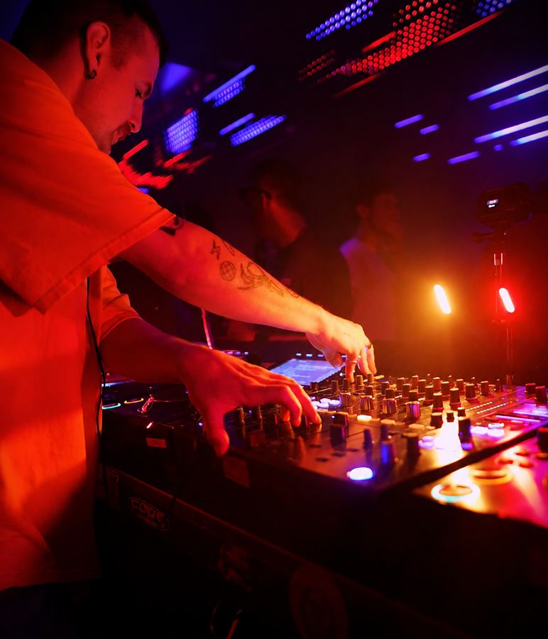 DJ mid-set, side profile, colourful lighting