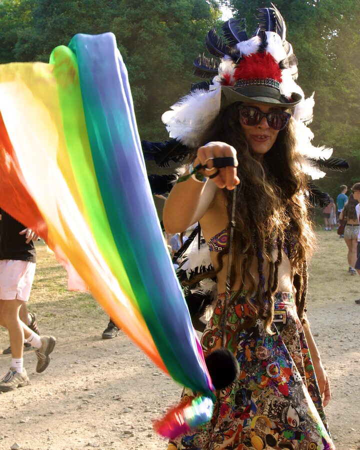Festival goer with rainbow flag, feather headdress